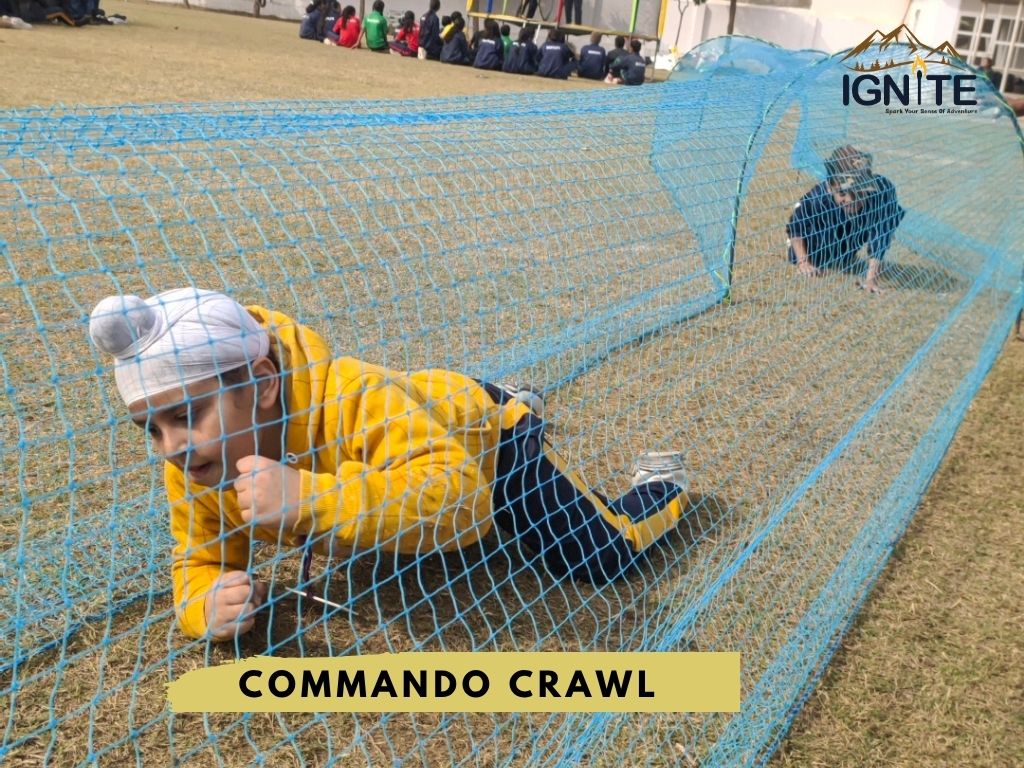 A student performing a commando crawl through a net tunnel