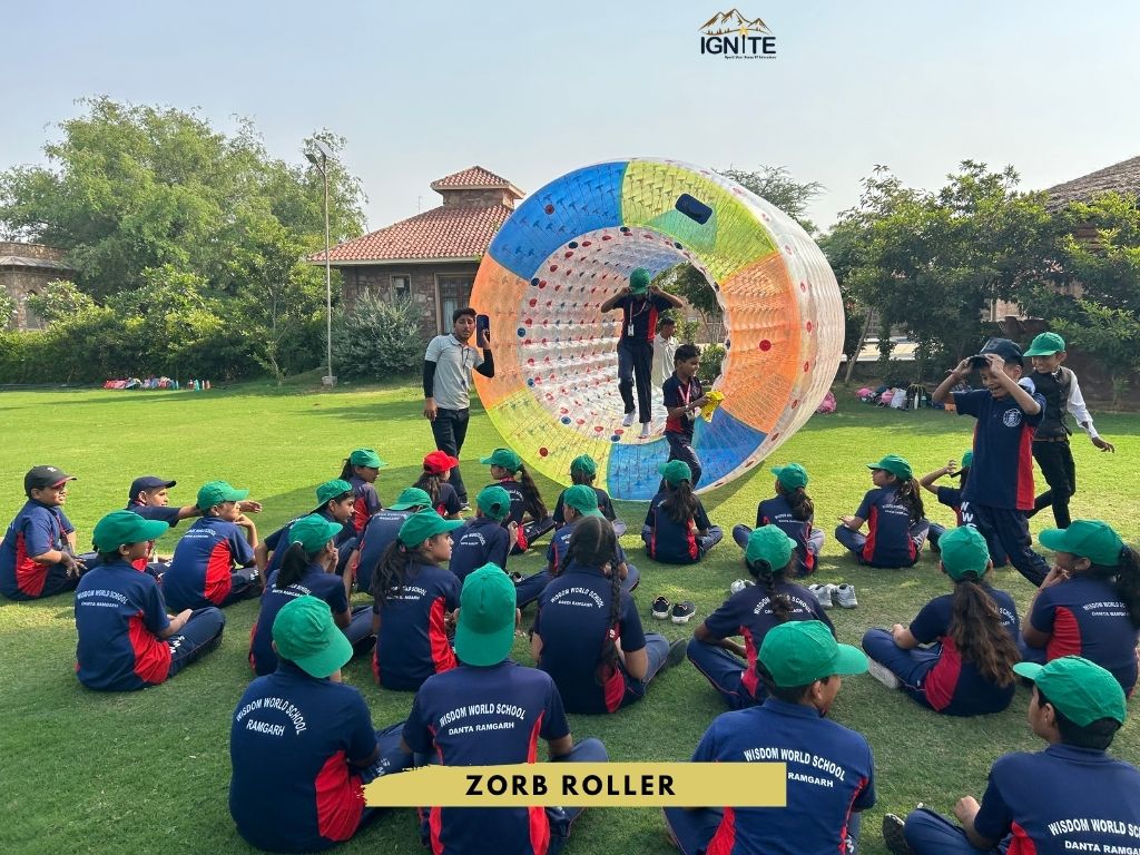 Students enjoying a zorb roller activity on a grassy field