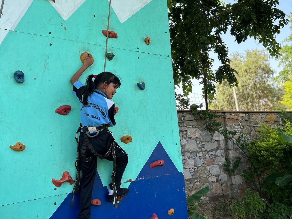 A girl in a harness climbing a rock wall