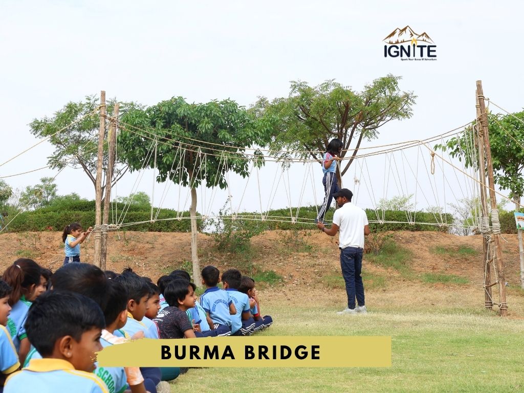 Students watching another student cross a Burma Bridge