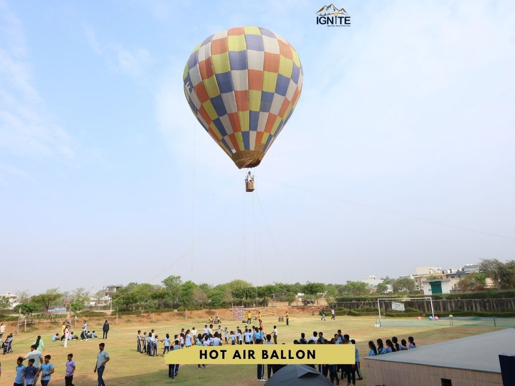 A hot air balloon being prepared on a field with students observing
