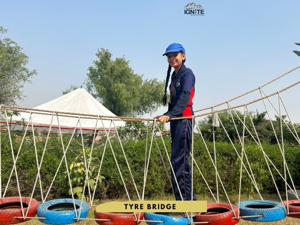 A student balancing on a Tyre Bridge obstacle